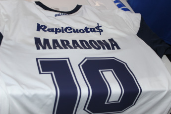 La Plata, Argentina.- En la imágen tomada hoy 6 de septiembre de 2019 en la sede del Club Gimnasia y Esgrima La Plata imágenes de la camiseta del club que comenzará a dirigir Diego Maradona en los próximos días con su nombre, que se vendía en la sede del club, abarrotada de simpatizantes queriendo asociarse al club.  Gimnasia y Esgrima La Plata es un modesto club de la ciudad de La Plata, la capital de la provincia de Buenos Aires, que aunque es uno de los clubes de fútbol más antiguos de la Argentina, nunca ha obtenido un campeonato oficial de primera división y actualmente pelea por no descender a segunda división. La venida de Maradona como Director Técnico es tomada por la institución como una oportunidad para generar más socios y vender su camiseta.