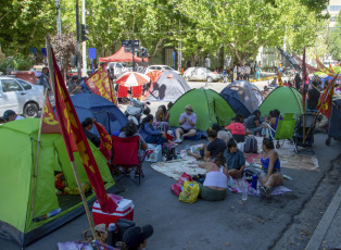 Neuquén, Argentina.- En las fotos tomadas el 30 de enero del 2024, movimientos sociales de Neuquén comenzaron un acampe en las puertas de la Casa de Gobierno provincial, en reclamo de la continuidad laboral de 740 familias y de un pago que estaba comprometido para el mes de diciembre, cuya falta "atenta contra la asistencia social a comedores".